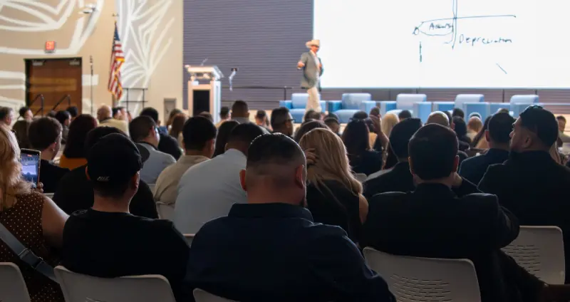 Auditorio lleno escuchando a Marcos en un taller de educación fiscal