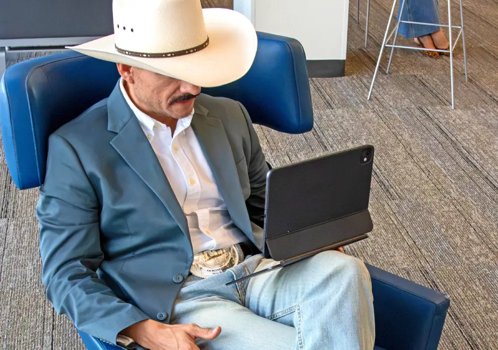 Marcos Ramírez revisando números en su tableta, sentado en una silla azul